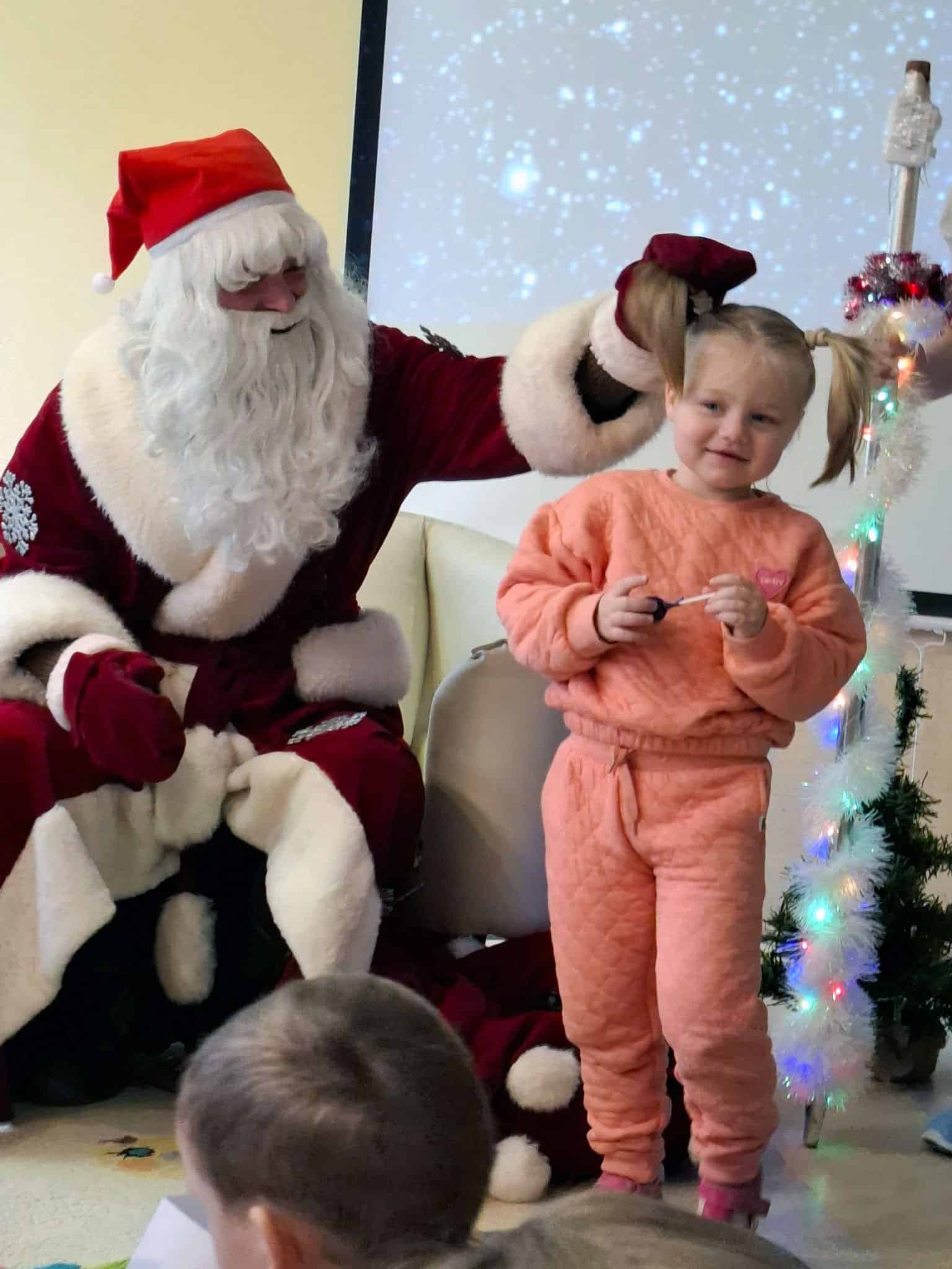 Nikolaus mit Mädchen im rosa Anzug und mit Zöpfen
